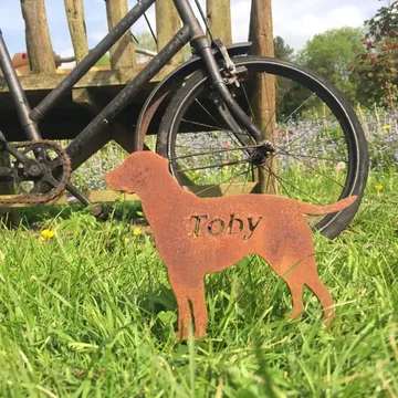 A laser-cut steel memorial marker engraved with the name Toby, in a garden
