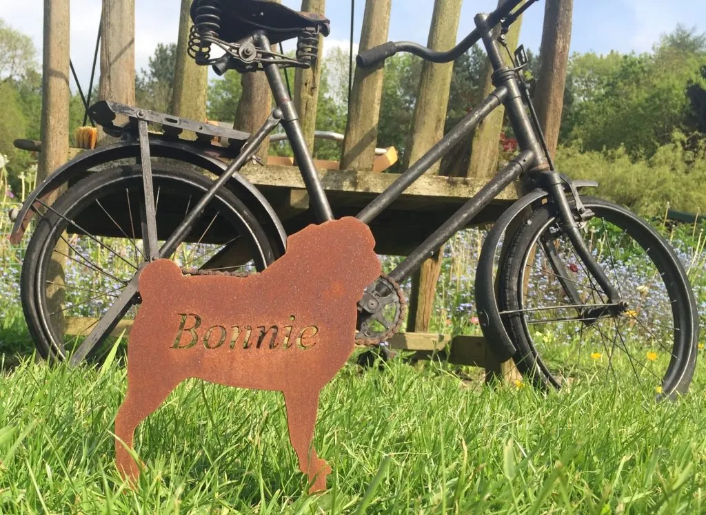 A laser-cut steel memorial marker engraved with the name Bonnie, in a garden